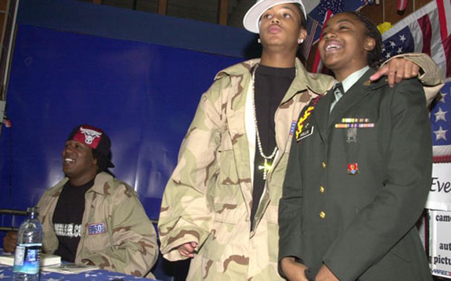 Master P, left, sits nearby while Lil’ Romeo poses for a photo Wednesday with Vilseck Middle and High School Junior Reserve Officer Training Corps cadet Tamaria Hollis at the Vilseck PX.