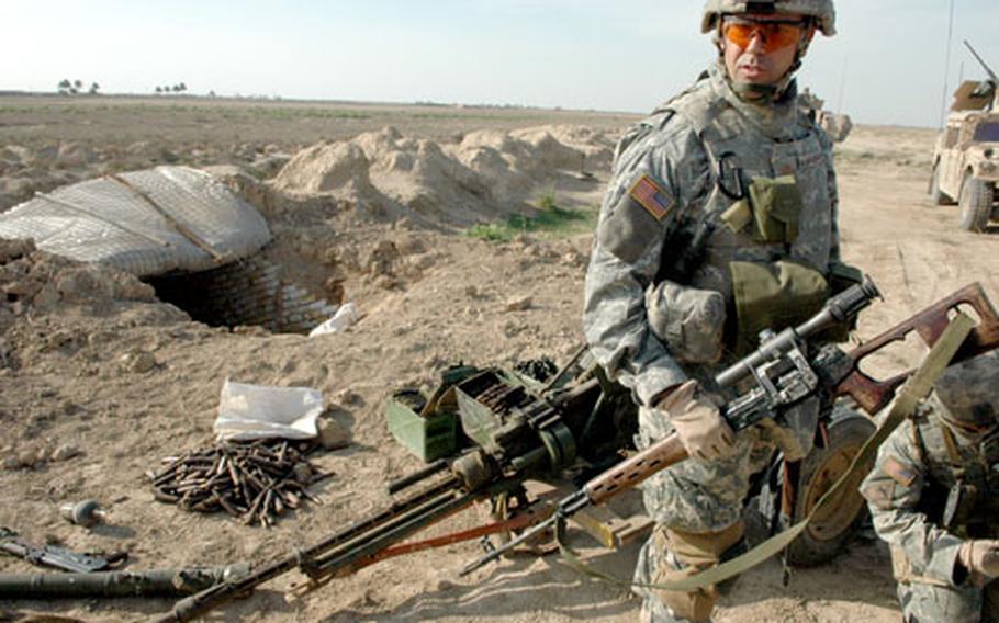 Maj. John Digiambattista inspects the anti-aircraft gun and other weapons found during the chase of several insurgents.