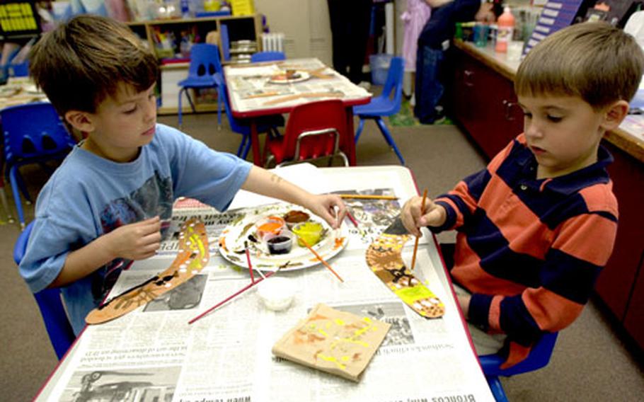 Zukeran first-graders J.J. Winchester, left, and Jacob Clement paint paper boomerangs during their visit to “Australia.” Each classroom studied a different culture and students traveled the world during 25-minute presentations.