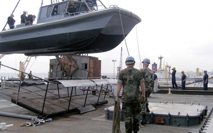 Sailors from Naval Support Activity La Maddalena Security Forces guide their Moose boat onto the crane deck for repairs on board the USS Emory S. Land. The sailors are providing harbor security during the Land’s deployment to the Gulf of Guinea.