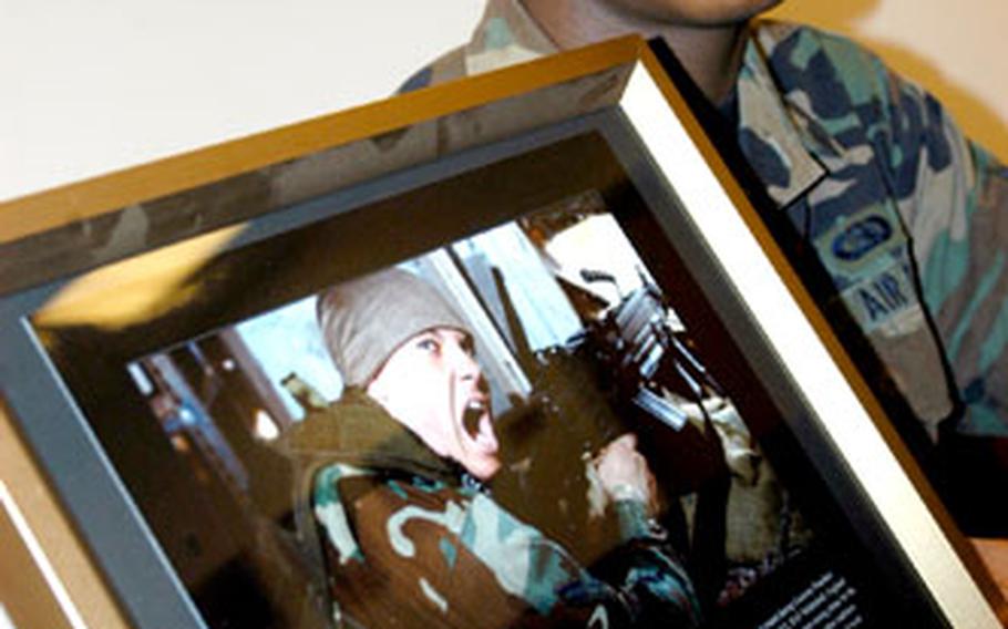 Airman 1st Class Cecil McCloud holds a photo of Airman 1st Class Daniel Nolan of the 100th Security Forces. The photo, taken during an exercise, was part of a portfolio that garnered McCloud a scholarship to Syracuse University for a yearlong photojournalism program.