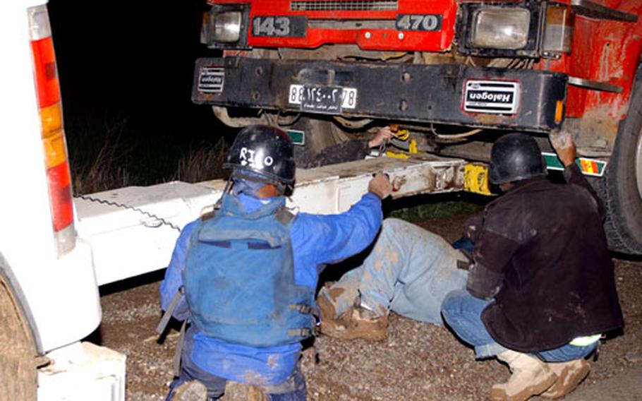 Personnel work to tow a stricken truck back to a U.S. base near Balad, Iraq. The driver blamed the breakdown on motor problems.