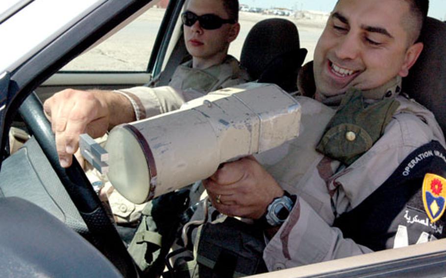 Senior Airman Philip Becker, 34, of San Marcos, Calif., uses a tuning fork to calibrate a radar gun at Iraq’s Ali Base Friday, as fellow military policeman and Senior Airman Brian Kasper, 20, of Tignall, Ga., looks on.