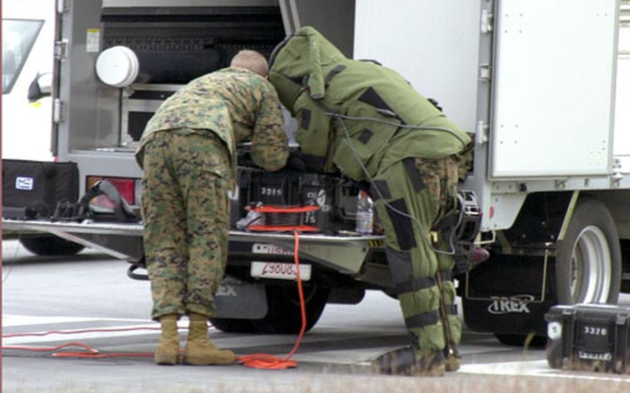 Members of Marine Wing Support Squadron 172 look at an X-ray of a suspicious package, which turned out to be a cooler containing Powerade and water, in the parking lot of the Camp Foster Exchange in November 2004. A nondeployable base explosive ordnance disposal team recently was formed to handle situations such as this, so other EOD teams can deploy with a full complement of Marines.