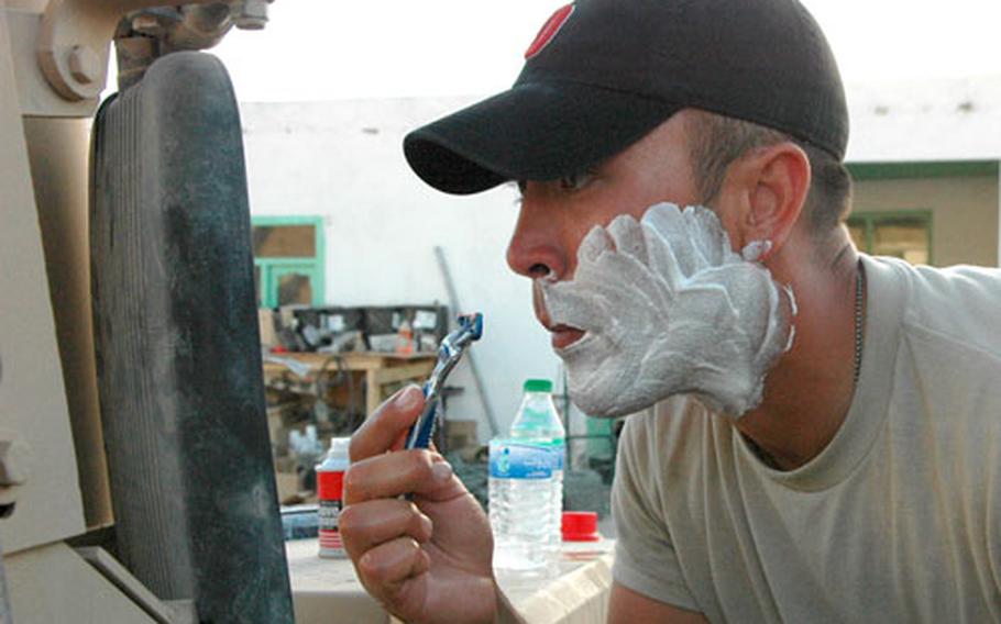 Staff Sgt. Timothy Pennartz, 29, from Dayton, Ohio, uses a Humvee mirror to shave at Forward Operating Base Mizan. Soldiers say they usually get one shower a week.