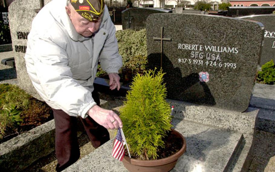 Veterans of Foreign Wars Tower Post Chaplain Joseph McCarthy places a flag on the grave of Sgt. 1st Class Robert Williams at the Grafenwöhr town cemetery.