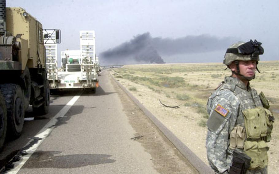 Pfc. Kenneth Pettigrew, of 1st Battalion, 77th Field Artillery Regiment, stands on the Iraqi roadside as his convoy is halted because of an accident ahead.