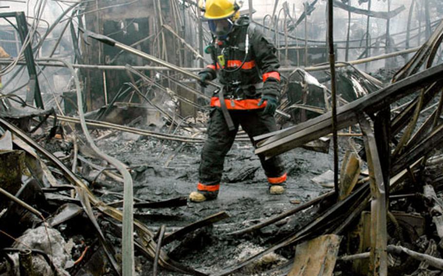 A firefighter walks through the remains of a DPW building on Yongsan Garrison, South Korea, on March 16.