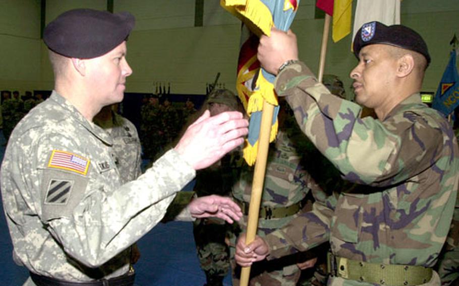 The 7th Army Noncommissioned Officer Academy commandant, Command Sgt. Maj. James F. Campbell, right, hands over the academy colors to Joint Multinational Training Command Commander Brig. Gen. David G. Perkins at a ceremony at Grafenwöhr, Germany, on Thursday.
