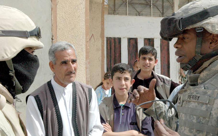 Sgt. 1st Class Melvin Perry, 33, of Atlanta, uses an interpreter to talk to residents in the Qadasiya neighborhood of Tal Afar, Iraq, one day prior to a roundup of military-age men there on Saturday. The neighborhood has been a refuge for insurgents, according to commanders.