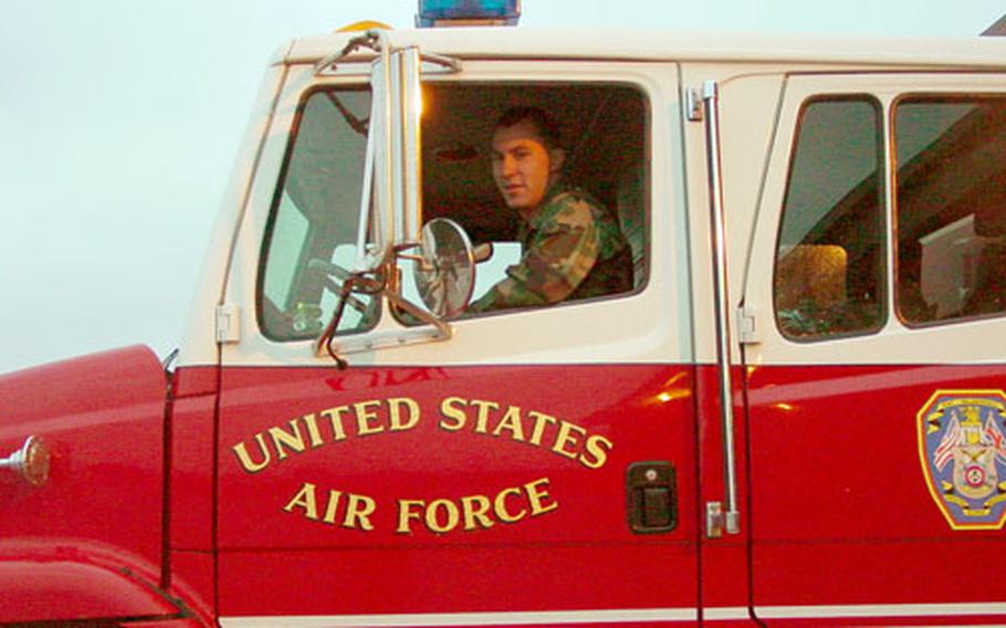 Airman 1st Class Paul Bradford, a firefighter for the 100th Civil Engineer Squadron, sits at the driver’s seat of a fire engine.