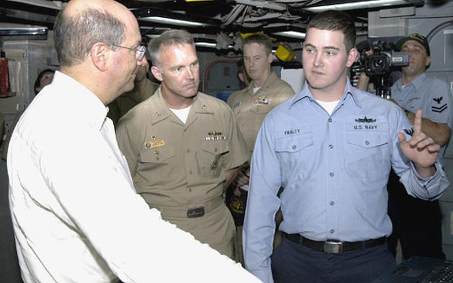 Secretary of the Navy Donald Winter listens as Petty Officer 2nd Class Owen Fraley, a cryptologic technician, explains the capabilities of the USS Emory S. Land's Combat Information Center Wednesday off the coast of Sekondi, Ghana. Winter visited Naples, Italy, on Friday.