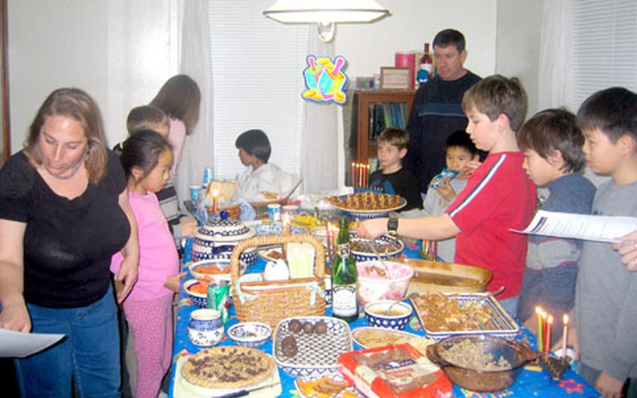 Camp Zama Jewish lay leader Laura Dadswell, left, organizes community events such as this potluck Hanukkah celebration at her house last year.
