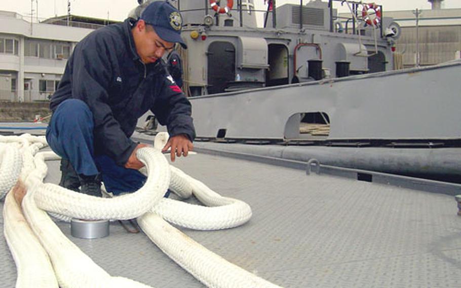 Petty Officer 2nd Class Gilbert Gumba splices a double-braided line in preparation for a morning of ship-moving Wednesday on one of Yokosuka Naval Base’s tugboats.