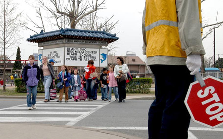 Students from Seoul American Elementary School on Yongsan Garrison, South Korea, cross 8th Army Drive on Monday afternoon. Crossing guards help the almost 2,500 students on Yongsan Garrison to and from school. Next year, Area II Support Activity’s budget has no money for the guards.