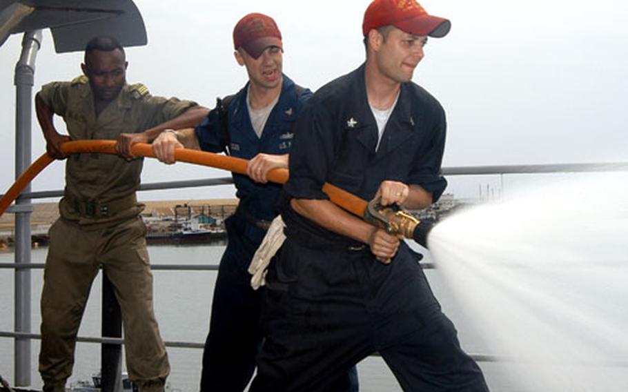 Sailors assigned aboard the submarine tender USS Emory S. Land, along with a member of the Congolese military, practice firefighting techniques. The Land and the USS Carr are wrapping up a two-month deployment to the Gulf of Guinea.