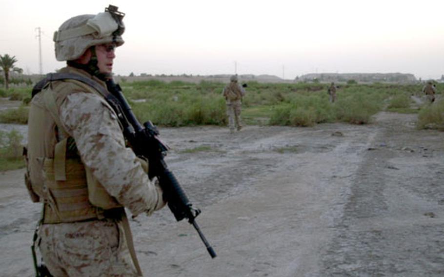 Members of a Mobile Assault Platoon assigned to the 3rd Battalion, 5th Marines patrol the road between Fallujah and Habbaniya, Iraq, as dusk settles.