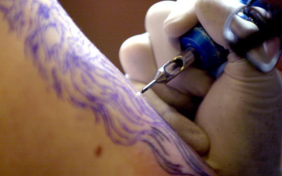 A tattoo needle goes to work on a sailor in Singapore.
