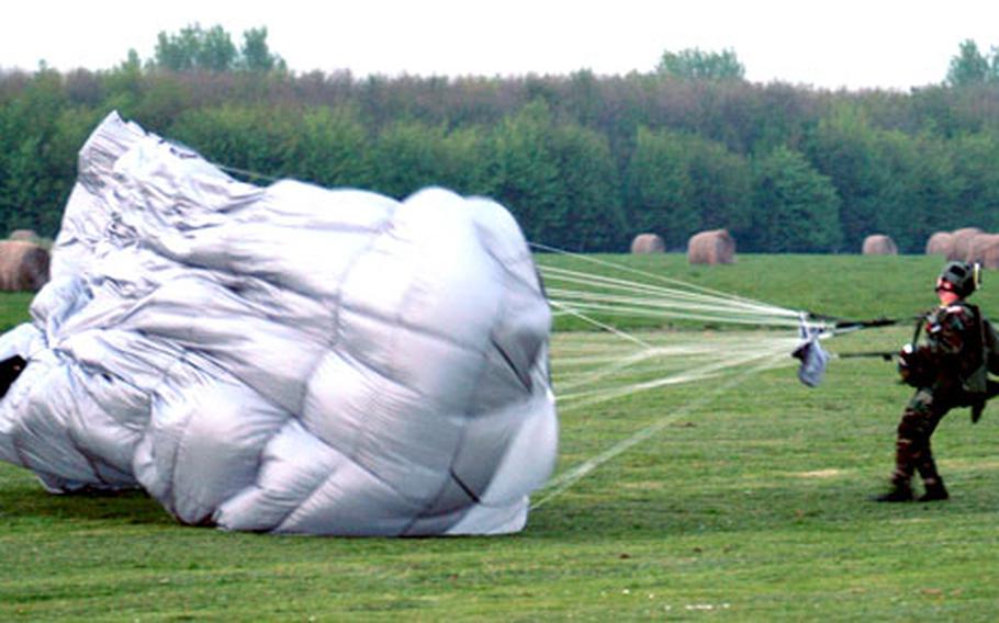 Maj. Claude Tudor, the 321st STS commander, pulls his parachute back from a drop zone after landing.