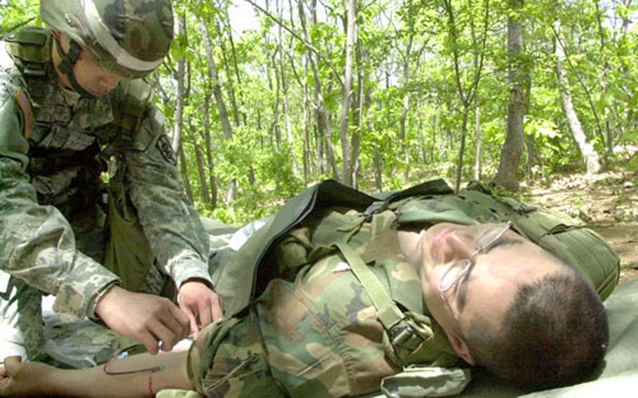 Sgt. Amarin Amnathavon of the 568th Medical Company sticks an intravenous needle into Pvt. Marcus Rios during Expert Field Medical Badge training at Warrior Base recently. Usually, fewer than 10 percent of those who take the EFMB test earn the badge.