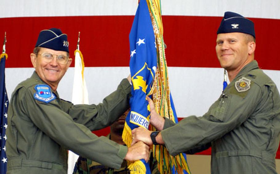 Lt. Gen. Garry Trexler, left, 7th Air Force commander, hands the 8th Fighter Wing’s guide on to Col. Jeffrey G. Lofgren during a change-of-command ceremony Monday at Hangar 3. Lofgren is the 45th Wolf — the name traditionally given the leader of the 8th Fighter Wing, which is known as the Wolf Pack.