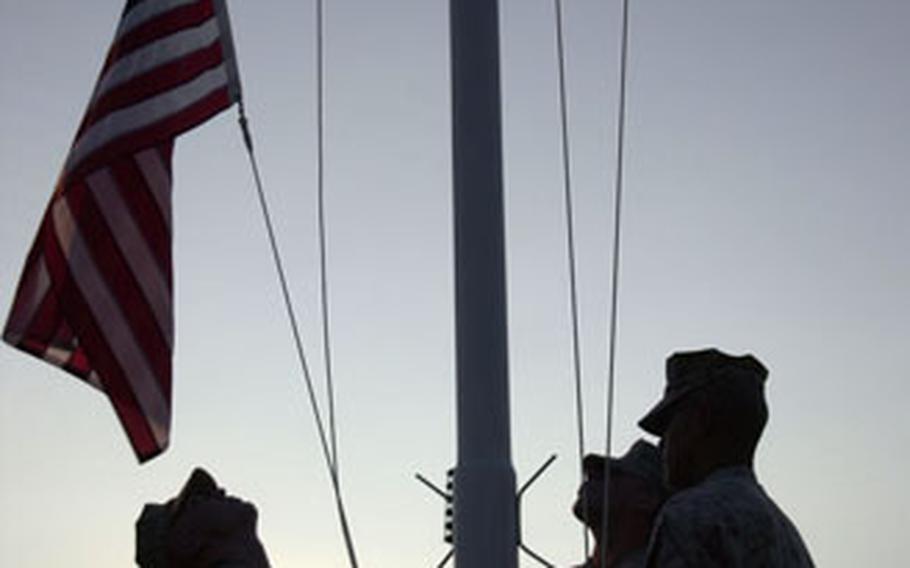 Members of a Marine security company lower the flag at sunset on Camp Lemonier last week.