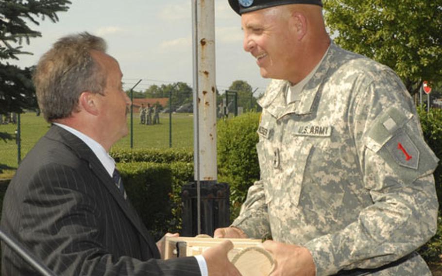 Maj. Gen. Kenneth W. Hunzeker, commander of the 1st Infantry Division, is presented a box of Franconian wine by Paul Merklin, burgermeister of Giebelstadt, Germany, during a retreat ceremony Friday at Giebelstadt Army Airfield.