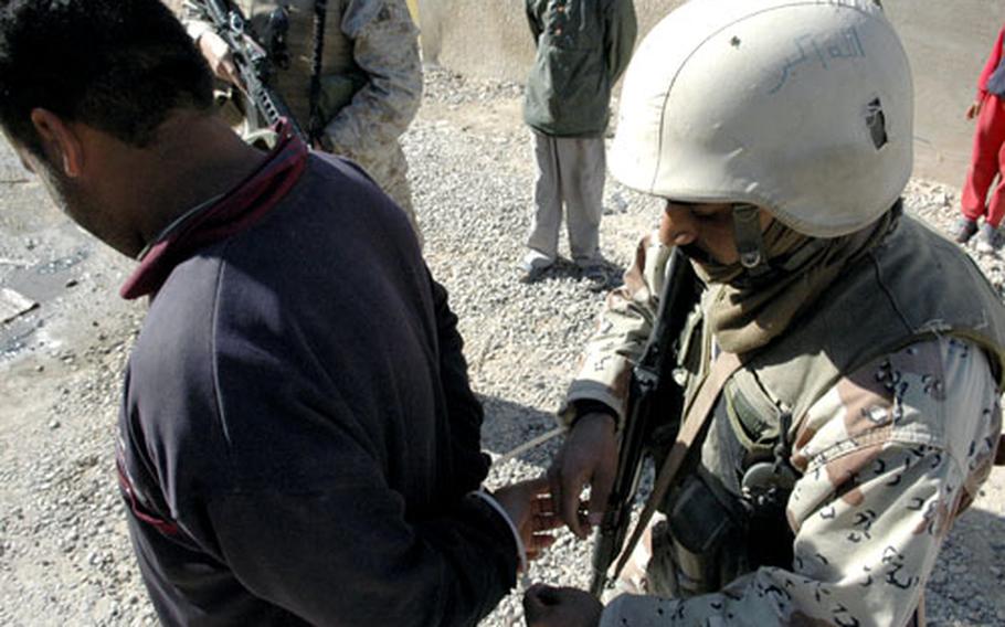 A suspected insurgent is handcuffed by an Iraqi soldier. There is an ongoing debate over the role of foreign fighters from countries like Syria and Saudi Arabia in Iraq’s insurgency.