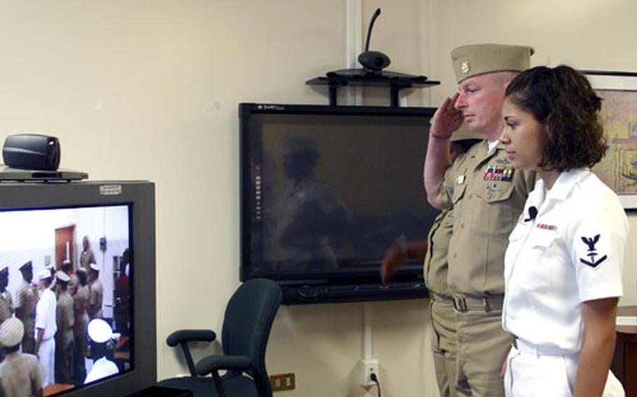 From her command at the naval hospital in Naples, Italy, on Friday, Petty Officer 3rd Class Lauren Williams watches as her mother, Senior Chief Petty Officer Rhonda John, retires an ocean away in Athens, Ga. With her is Master Chief Petty Officer Kevin Kesterson, command master chief of the hospital.