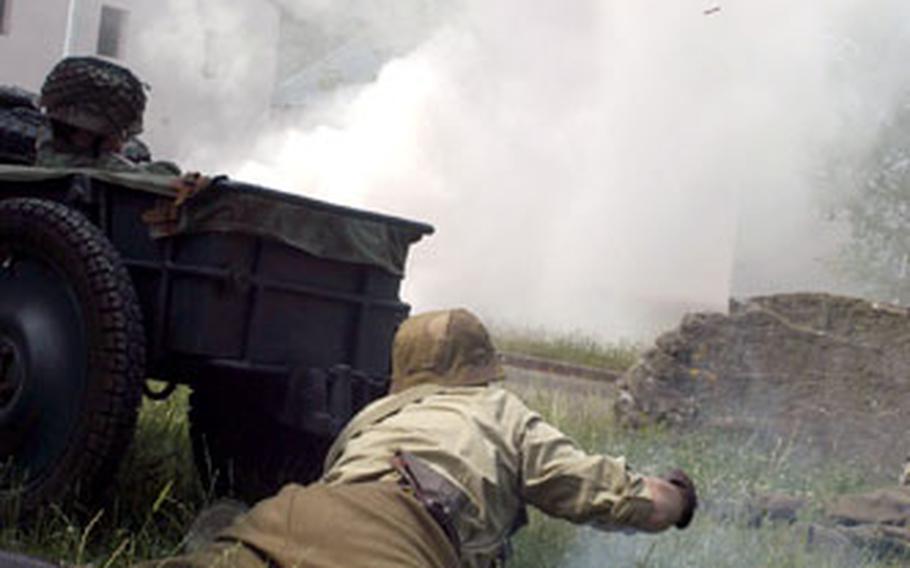 A German soldier throws a smokegrenade to conceal the movement of his troops flanking the village during the re-enactment.