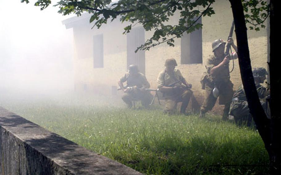 Behind a thin veil of smoke, a team of German troops waits to advance on Allied forces during a World War II re-enactment in Baumholder on Saturday.