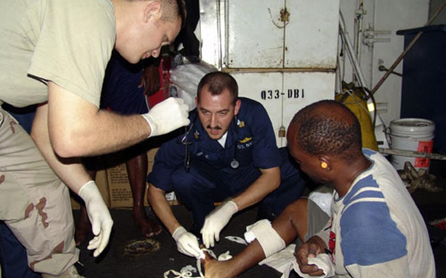 Aboard the USS Reuben James, Petty Officer 1st Class Matthew Breske, center, and Seaman Justin Brandenburg, left, treat a Kenyan fisherman after rescuing him from the Arabian Sea.