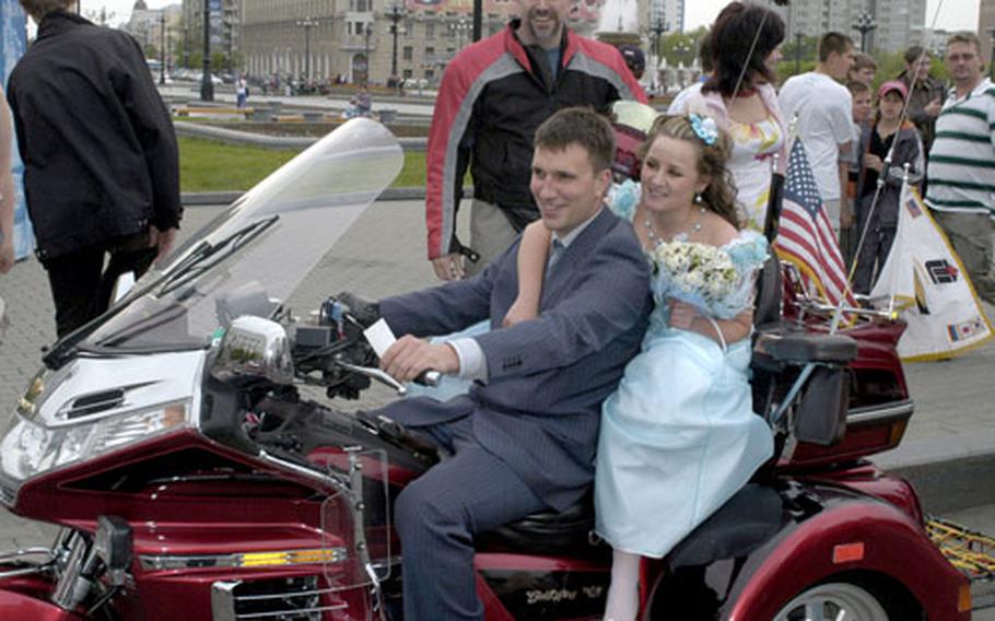 U.S. Forces Korea civilian Dave Darby, standing, lets Russians from a wedding party hop on his Lehman Trike-modified Honda Gold Wing in Khabarovsk on June 1.