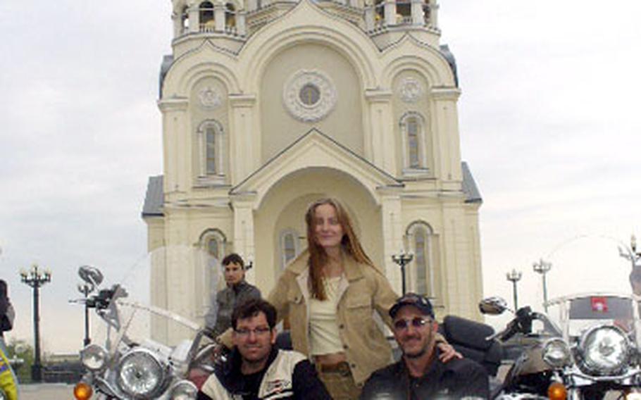U.S. Forces Korea civilians Clay Allison and Robert Soska pose with a motorcycle admirer during the Americans’ journey through Russia.