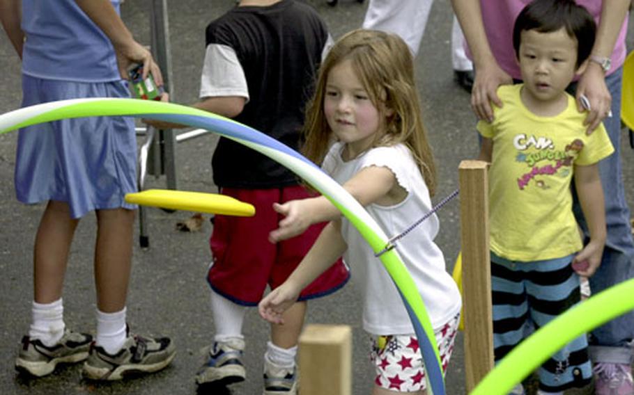 A young girl throws a Frisbee through a Hula-Hoop target during a Fourth of July celebration on Yongsan Garrison.