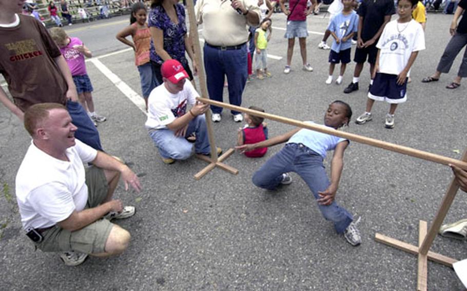 Tirzah Sheppard slides under the limbo pole as Area II commander Col. Ron Stephens, on left, judges the competition at the Fourth of July celebration on Yongsan Garrison, South Korea.