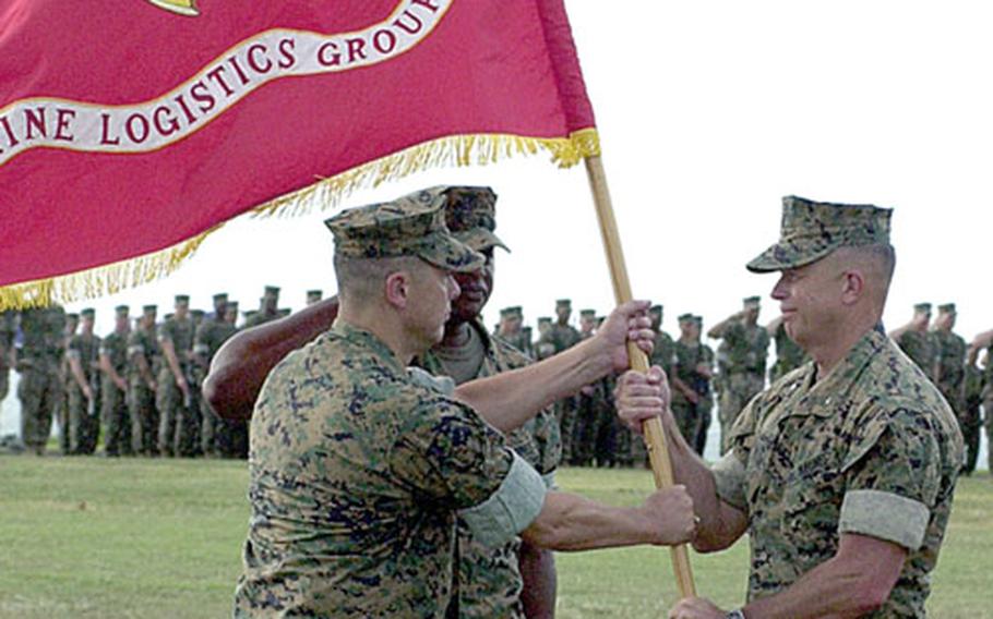 Brig. Gen. Peter J. Talleri takes the 3rd Marine Logistics Group colors from Brig. Gen. Frank Panter, symbolically accepting command of the group, during the change-of-command ceremony at Camp Kinser, Okinawa.