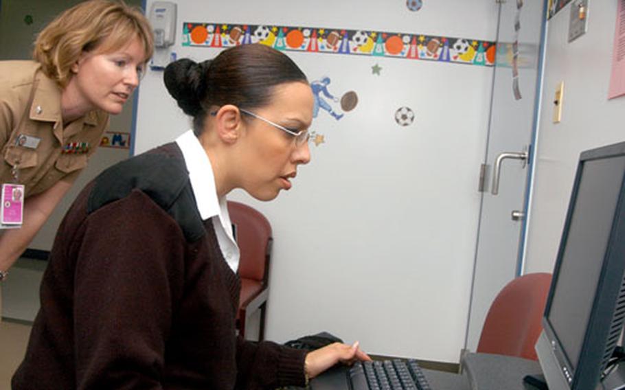 Cmdr. Lynn Bailey, left, director of Medical Services at U.S. Naval Hospital Yokosuka, works with Petty Officer 3rd Class Charity Wilson. Wilson said going paperless at the hospital may cause some difficulty initially but will make things better in the long run.