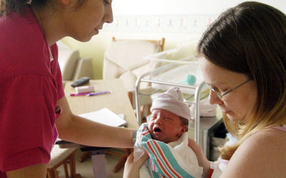 Civilian nurse Crystal Hyatt helps Jennifer Kells with 1-day-old baby Madison at Naval Hospital Yokosuka on Thursday.