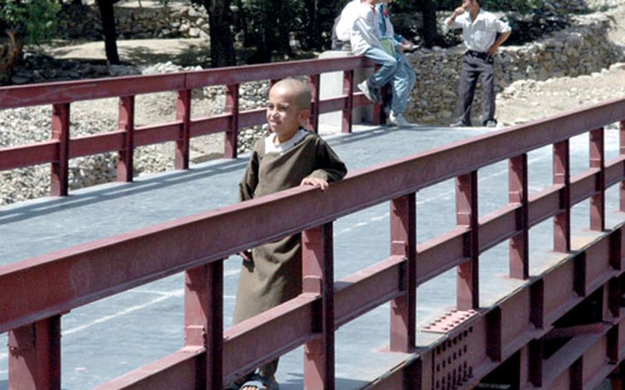 A young Afghan boy waits for a friend to catch up after running across the newly finished bridge outside Nawaj, Afghanistan, on Tuesday.