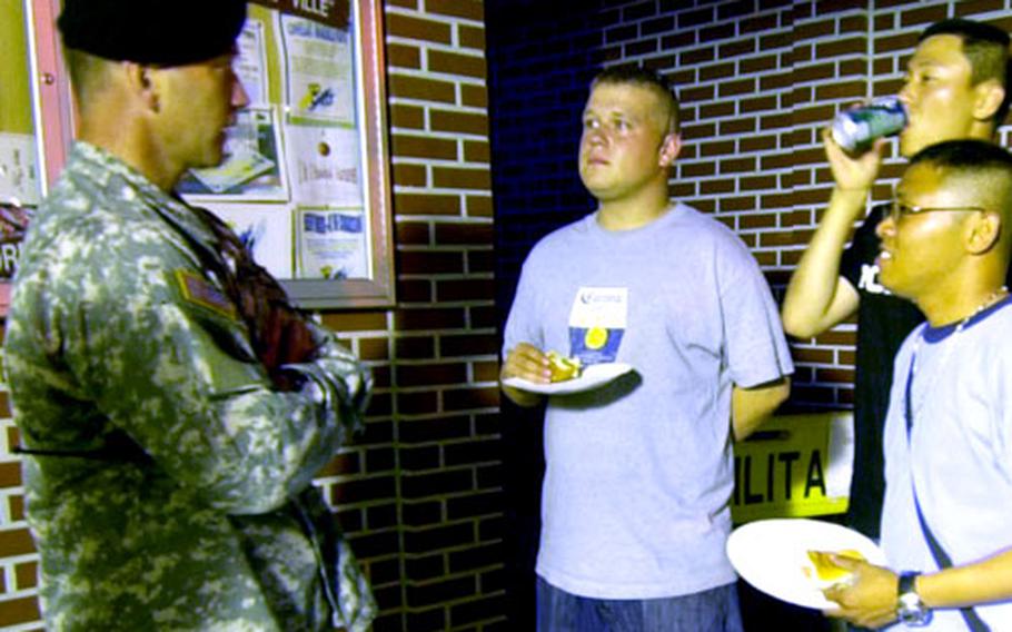 Area III commander Col. Michael J. Taliento Jr., left, chats with a group of soldiers before they walk off Camp Humphreys into the Anjung-ri bar district on July 7.