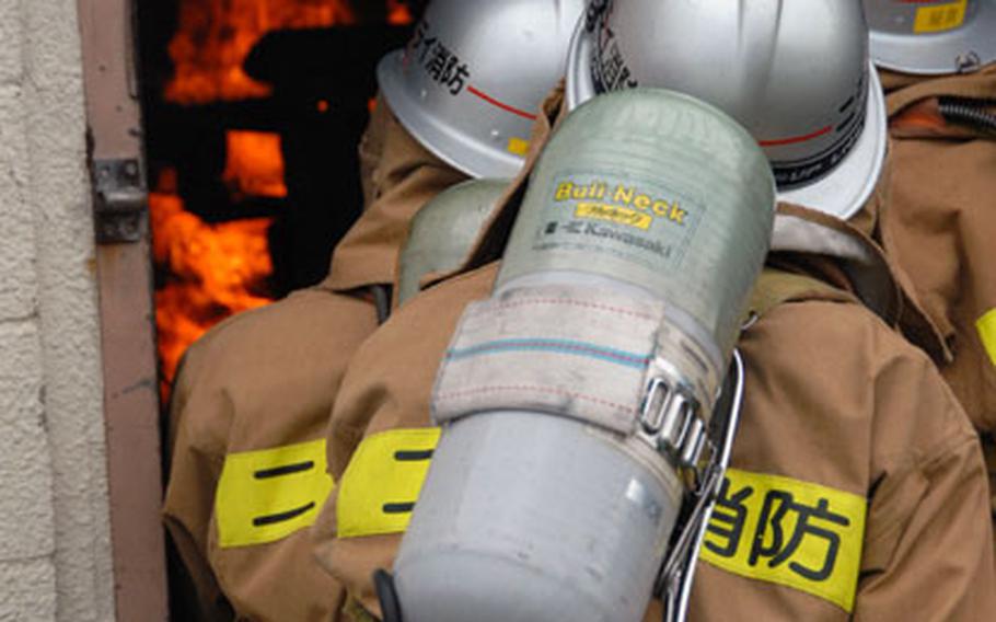 Three Nirai Fire Department firefighters enter a burning building during the joint training exercise at Kadena Air Base with the 18th Engineer Squadron.