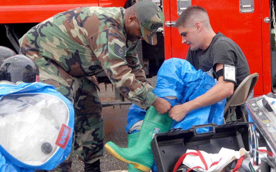 Senior Airman Jeremy McLendon of the 18th Civil Engineer Squadron gets help putting on his hazmat suit during an emergency response joint training exercise at Kadena Air Base.