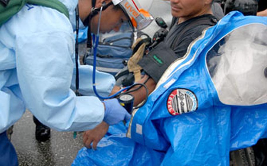 A medic with the Nirai Fire Department takes the vitals of a firefighter preparing to put on a hazmat suit Friday.