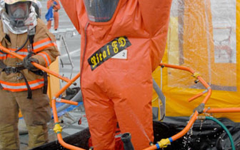 An emergency responder with Nirai Fire Department gets washed down Friday during the decontamination process after cleaning up “hazardous” material at a joint training exercise at Kadena Air Base.