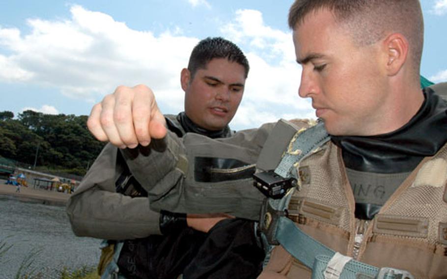 Maj. Mike Briggs, left, helps fellow F-16 pilot Capt. Scott Wuenstel zip into several layers of flight gear, to include a water-tight “poopy suit.”