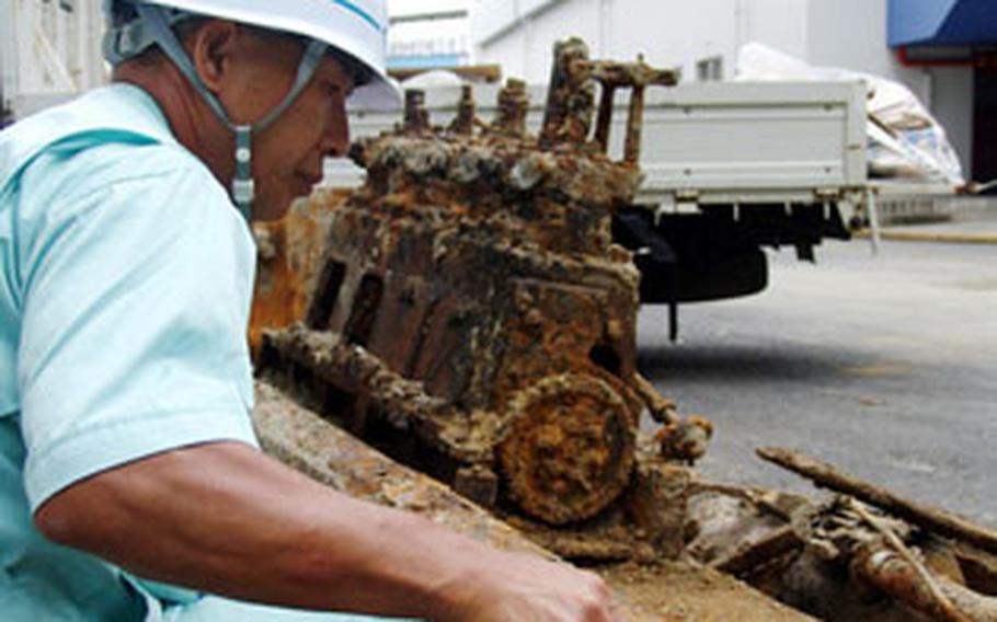 A World War II-era engine, unearthed recently at Yokosuka Naval Base, Japan, is inspected by Tsunehiro Ogata, Nikkai Corp. safety officer.