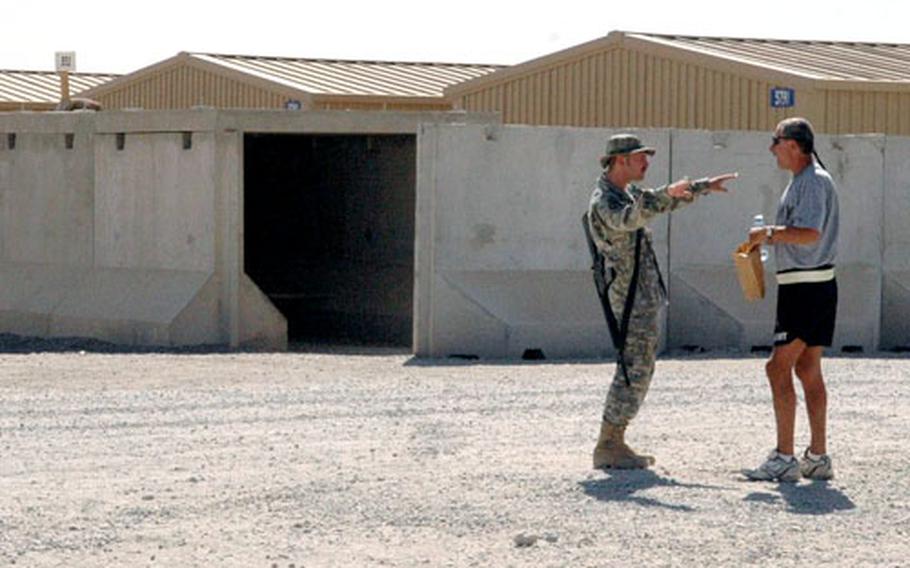 Staff Sgt. James Hilton, left, and Sgt. 1st Class Leslie Zaricor, both of the Army’s 1st Battalion, 210th Aviation Regiment, chat beside bunkers near their barracks the day after two mortar rounds struck Kandahar Airfield. Troops here say the attacks are becoming more annoying than frightening.