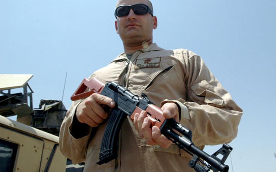 Marine Capt. Brian Hasheider holds a realistic-looking toy AK-47 assault rifle Sunday after confiscating several of them from Fallujah merchants. Commanders with the 1st Battalion, 25th Marine Regiment fear that children carrying the toys could draw fire from Marines patrolling the city.