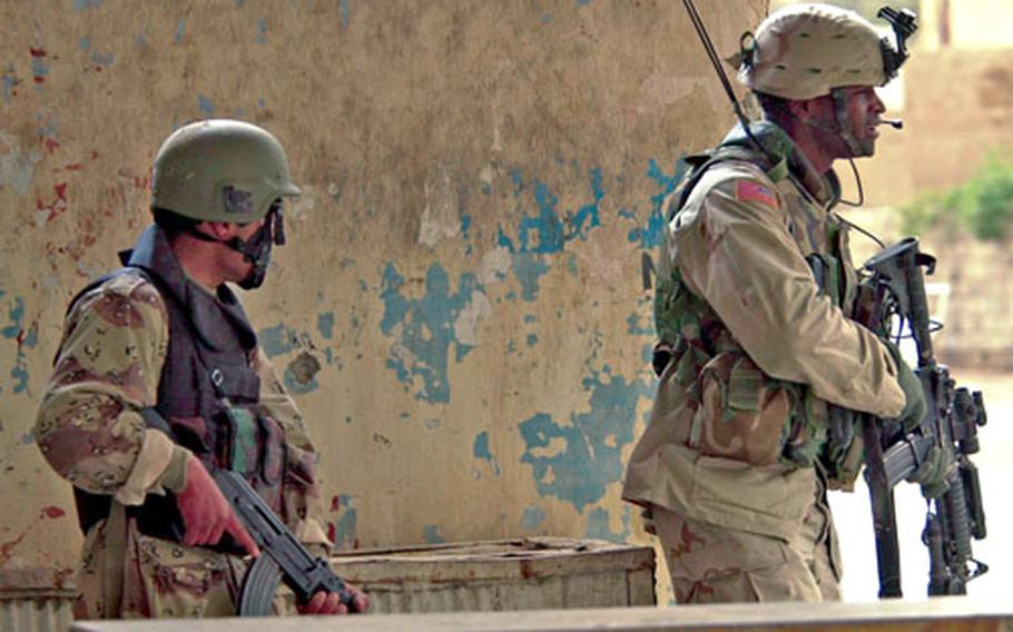 An Iraqi Special Police commando, left, and U.S. Army 1st Lt. Larry Chappell keep security on a street corner during a cordon and search operation last year in Ramadi, Iraq.